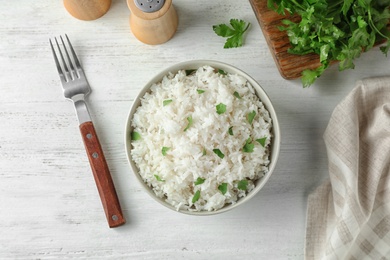 Photo of Bowl of boiled rice served on wooden table, top view