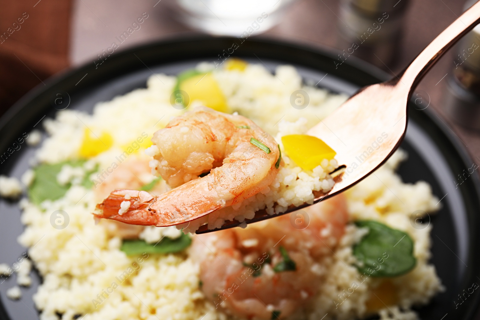 Photo of Fork with tasty couscous over plate, closeup