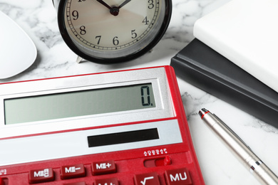 Photo of Calculator, alarm clock and notebooks on marble table, closeup. Tax accounting