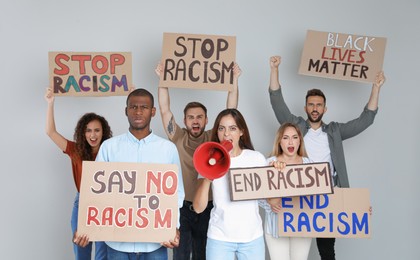 Photo of Protesters demonstrating different anti racism slogans on light background. People holding signs with phrases
