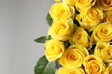 Beautiful bouquet of yellow roses on grey background, closeup. Space for text