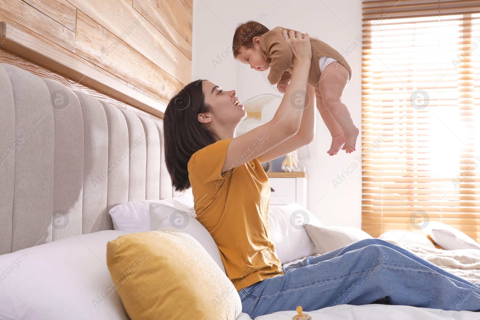 Photo of Happy young mother with her cute baby on bed at home