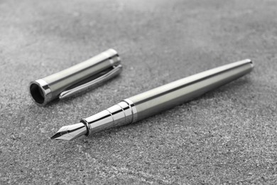 Photo of Stylish silver fountain pen on grey textured table, closeup