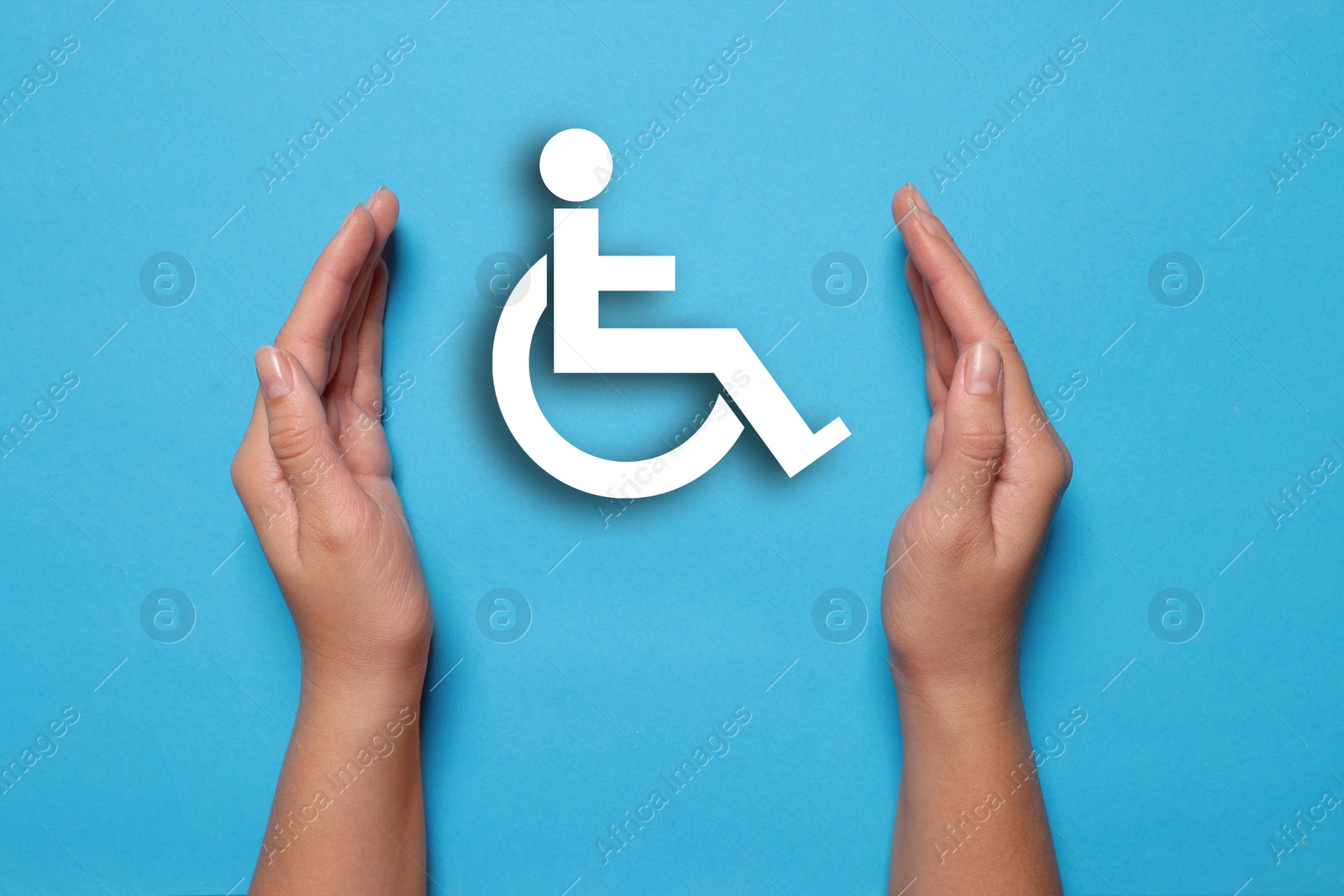 Image of Disability inclusion. Woman protecting wheelchair symbol on light blue background, closeup