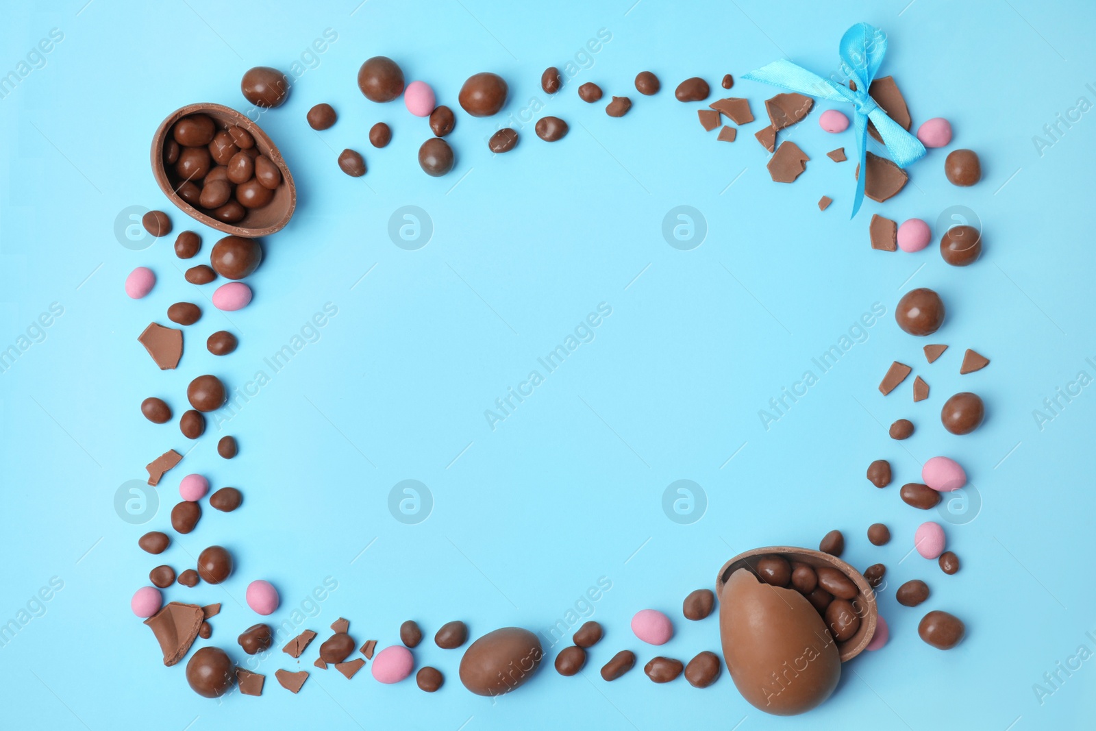 Photo of Frame of delicious chocolate Easter eggs on light blue background, flat lay. Space for text