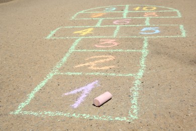 Photo of Hopscotch drawn with colorful chalk on asphalt outdoors, closeup