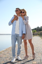 Happy couple walking along waterfront on summer day