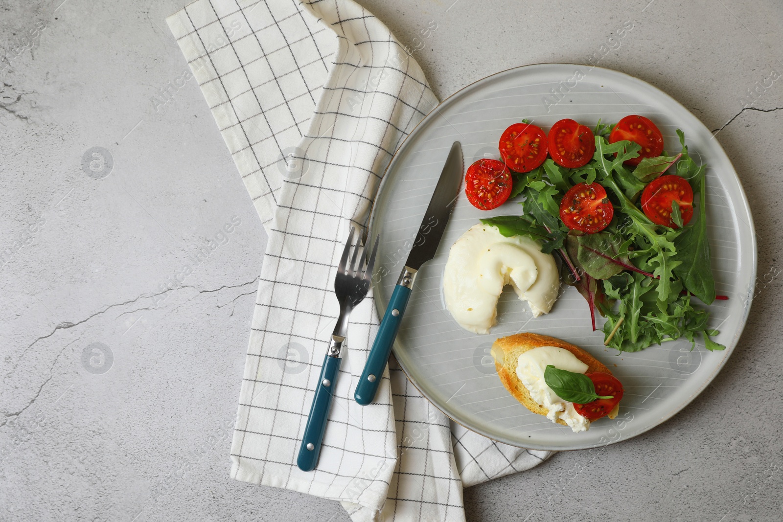 Photo of Delicious burrata cheese with tomatoes, arugula and toast served on grey table, top view. Space for text