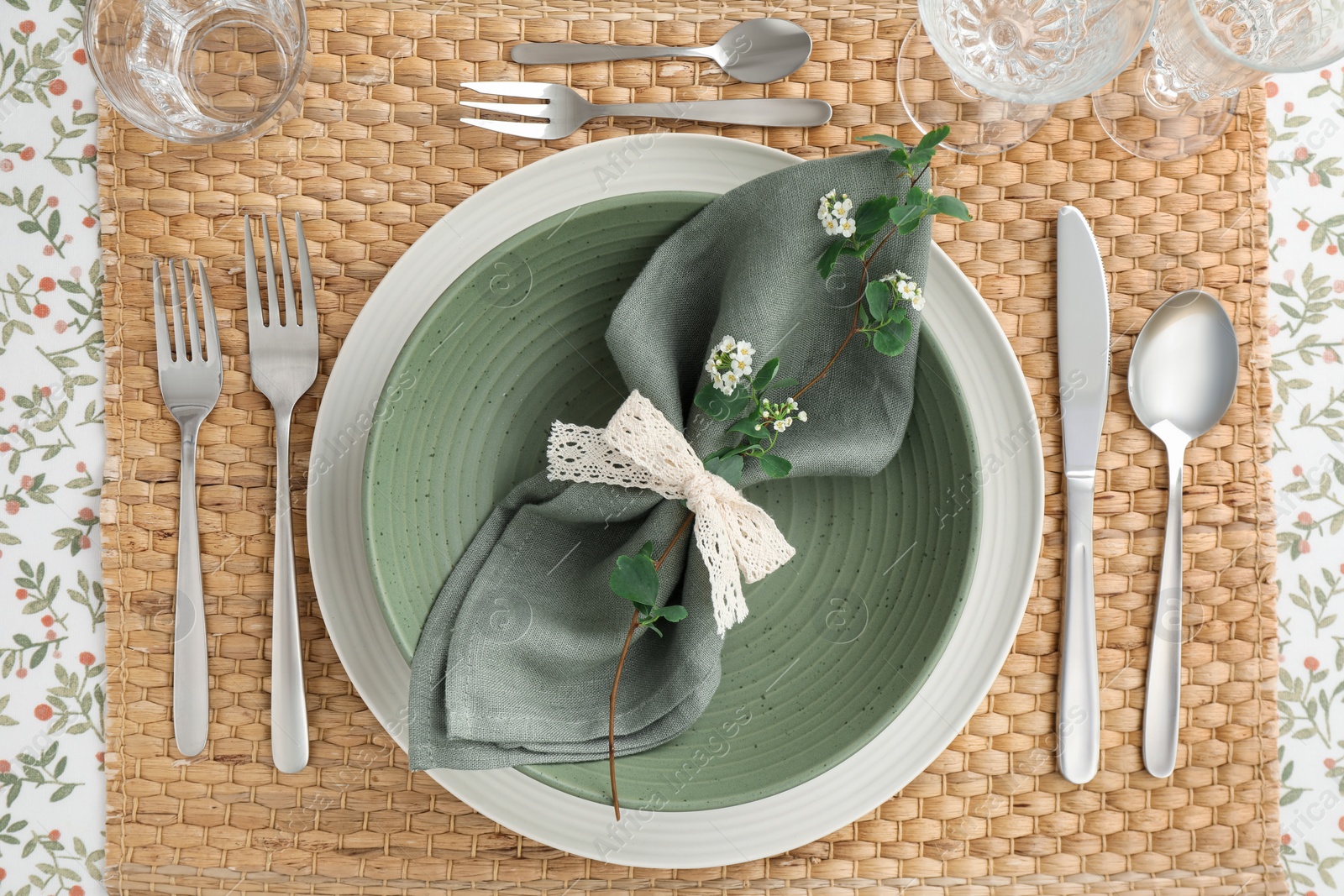 Photo of Stylish setting with cutlery, plates, napkin, glasses and floral decor on table, top view