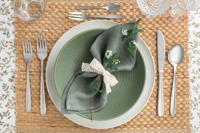 Stylish setting with cutlery, plates, napkin, glasses and floral decor on table, top view