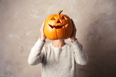 Photo of Woman holding Halloween pumpkin head jack lantern against color background