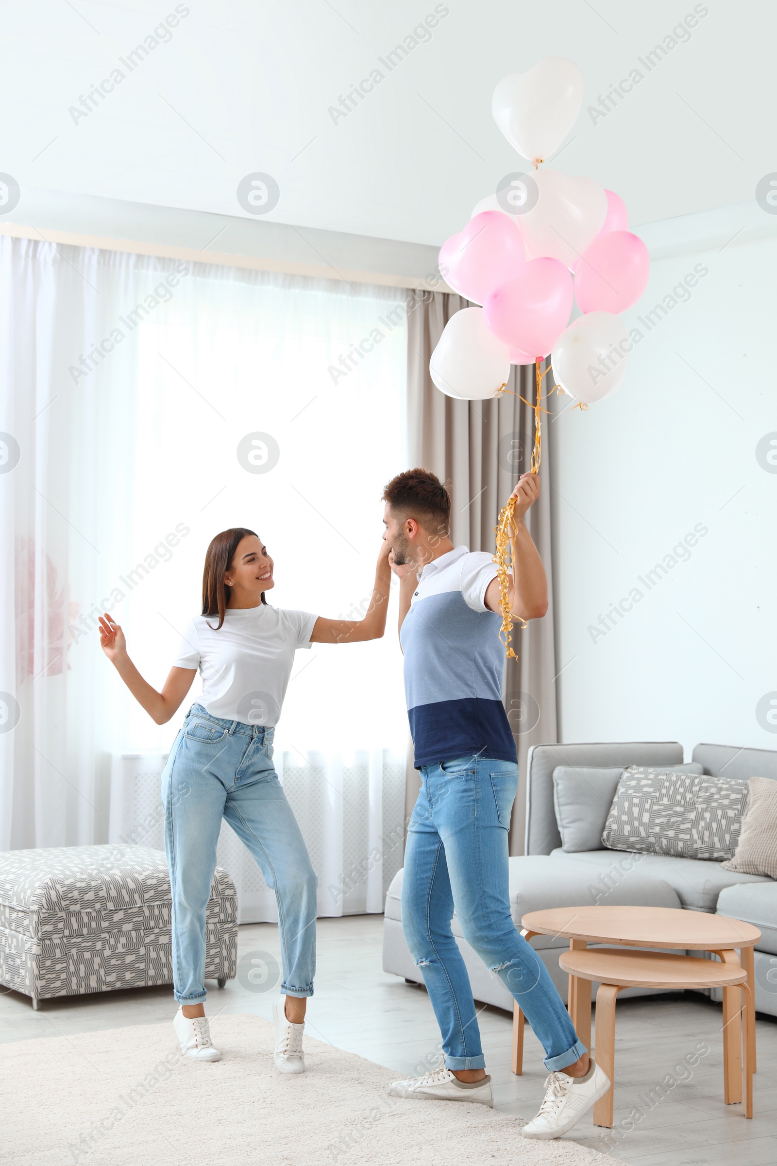 Photo of Young couple with air balloons at home. Celebration of Saint Valentine's Day