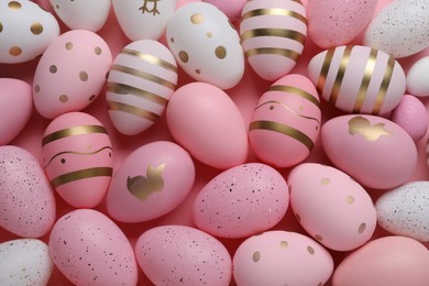 Photo of Many painted Easter eggs on pink background, flat lay