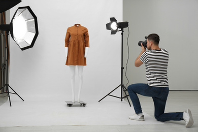 Professional photographer taking picture of ghost mannequin with stylish clothes in modern photo 
 studio