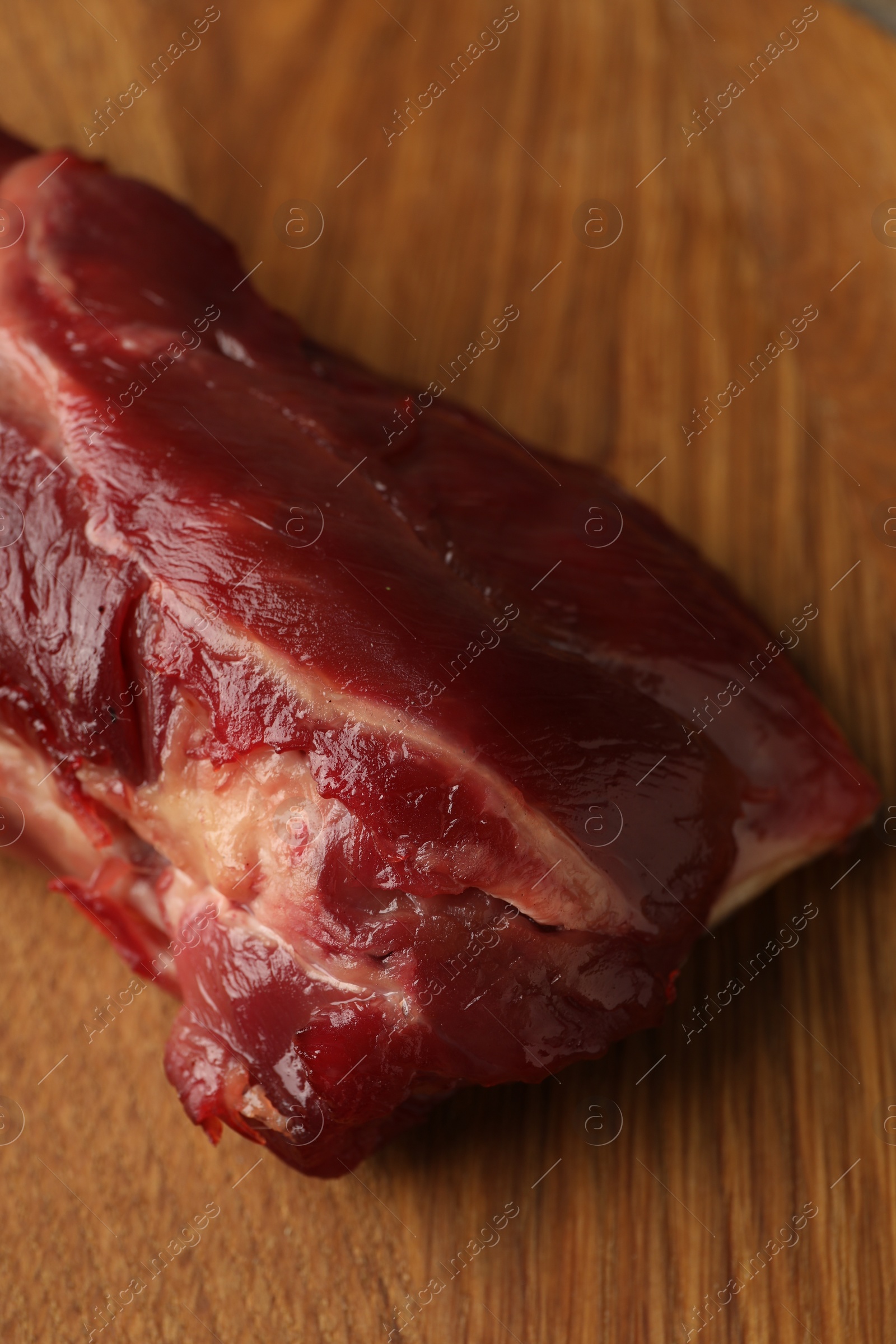 Photo of Piece of raw beef meat on wooden board, closeup