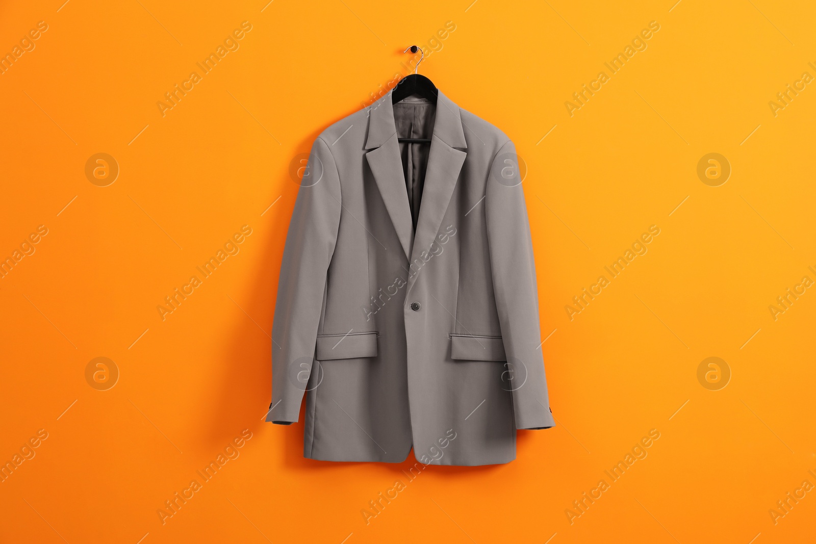 Photo of Hanger with grey jacket on orange wall