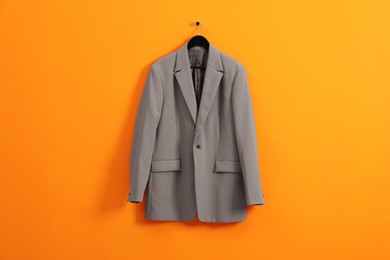 Photo of Hanger with grey jacket on orange wall