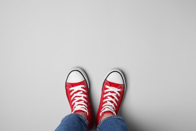 Photo of Woman in stylish gumshoes on light background, top view. Space for text