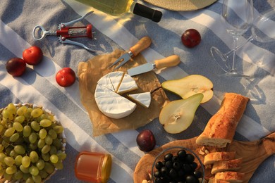 Photo of Different tasty snacks on picnic blanket, flat lay