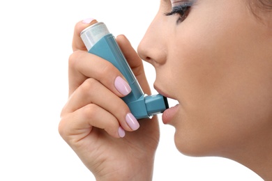 Young woman using asthma inhaler on white background, closeup