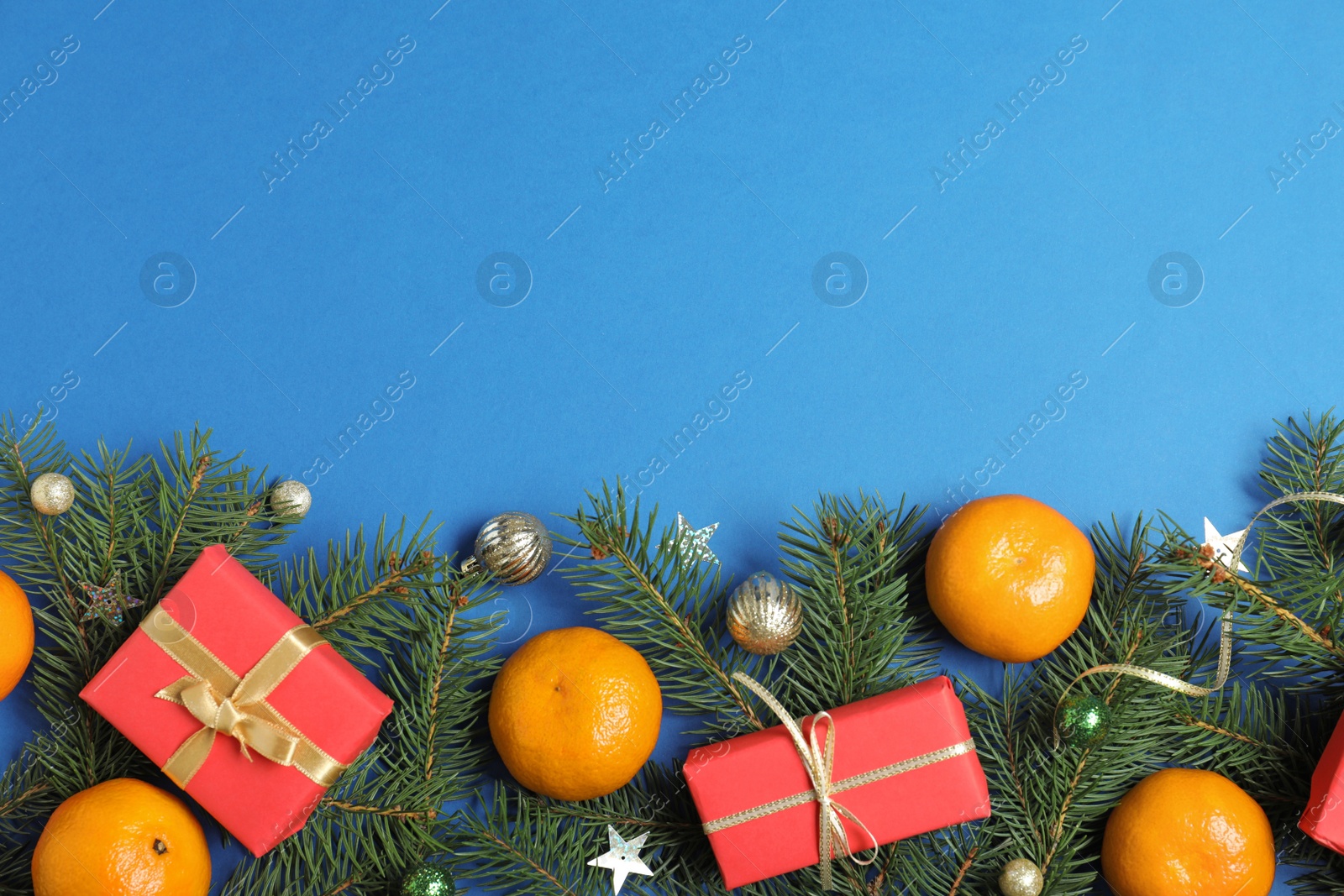 Photo of Flat lay composition with ripe tangerines, fir branches and Christmas decor on blue background. Space for text