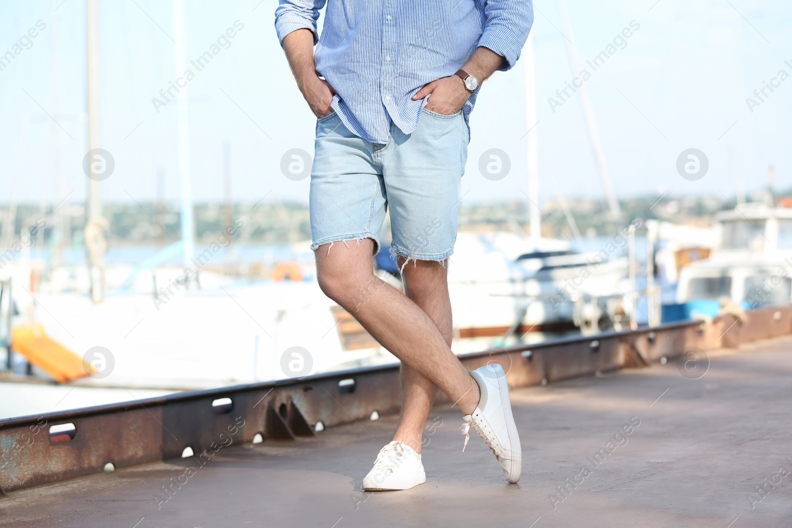 Photo of Young hipster man in jean shorts on pier