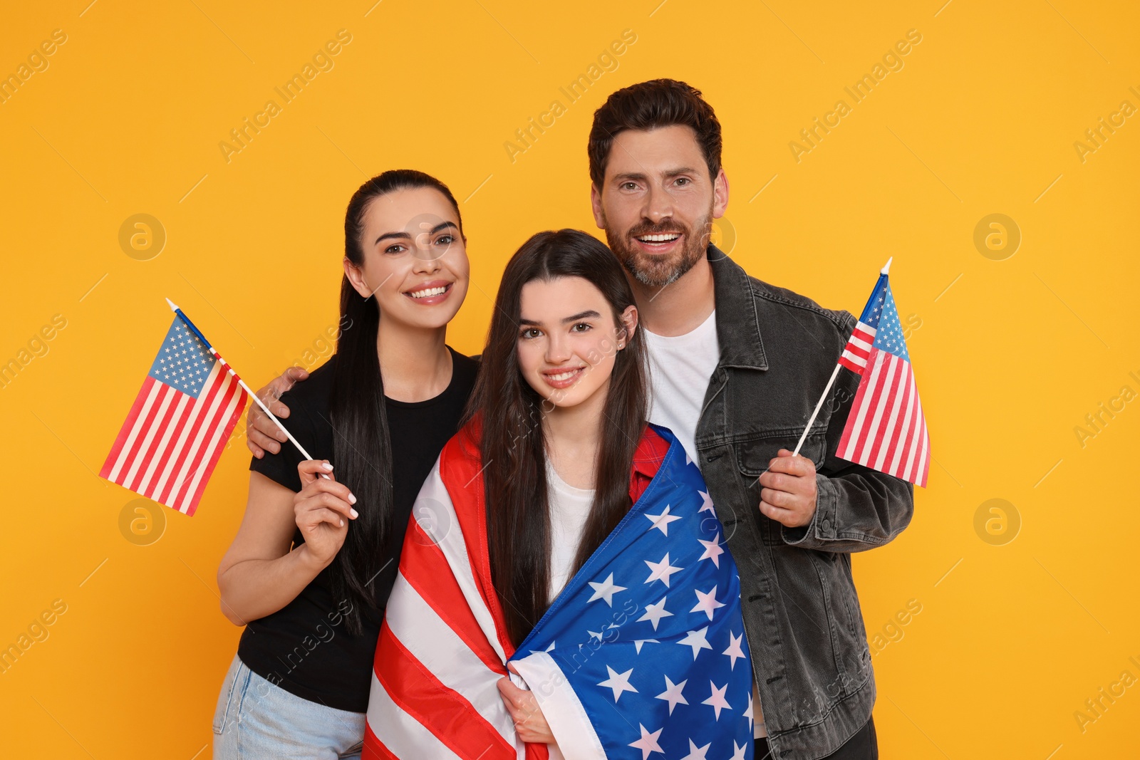 Photo of 4th of July - Independence Day of USA. Happy family with American flags on yellow background