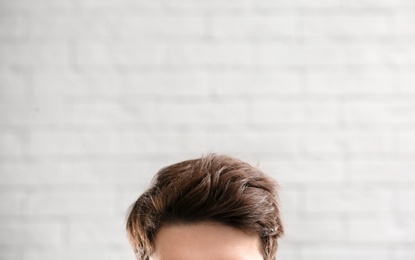 Young man with beautiful hair on brick wall background, closeup