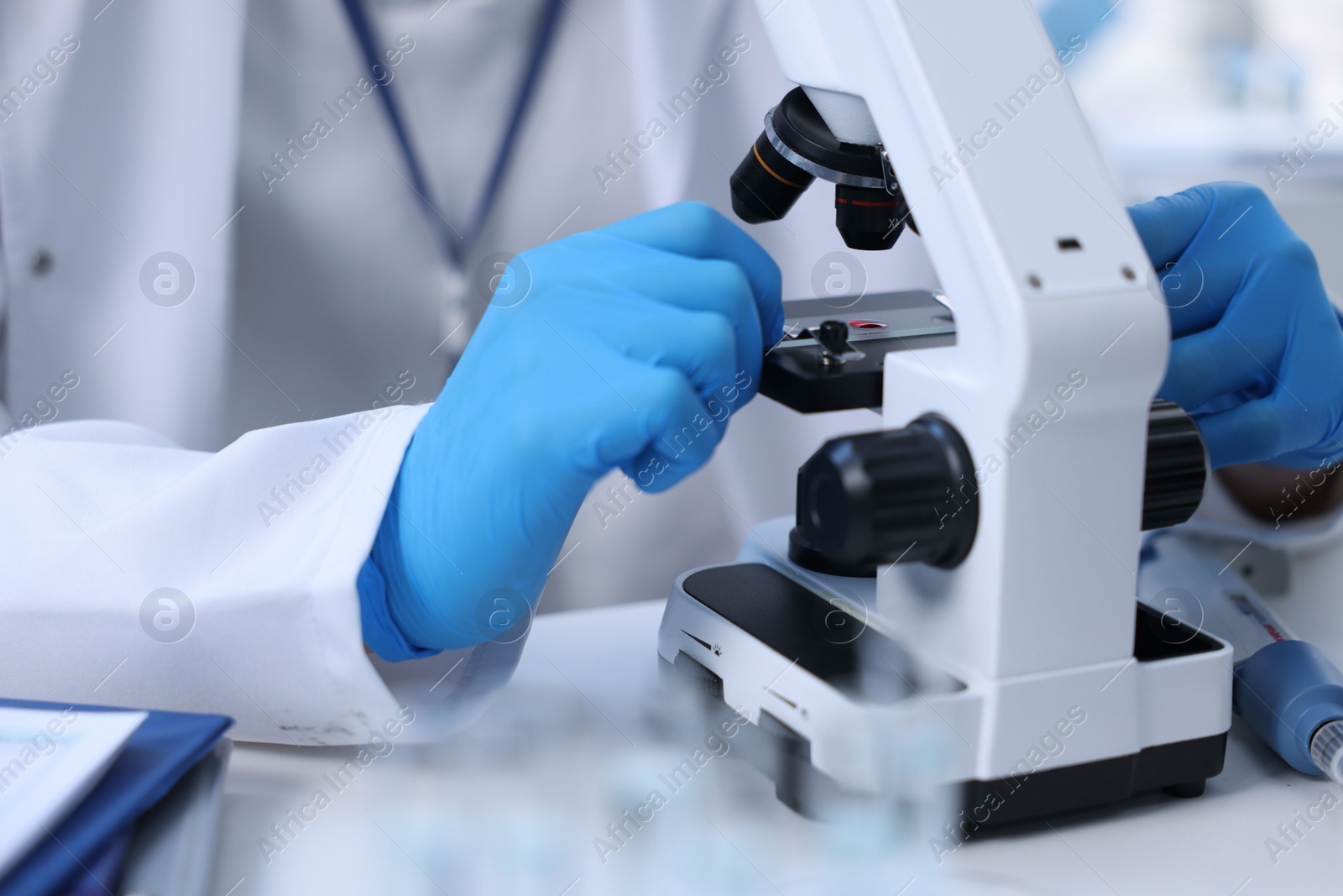 Photo of Scientist working with microscope in laboratory, closeup