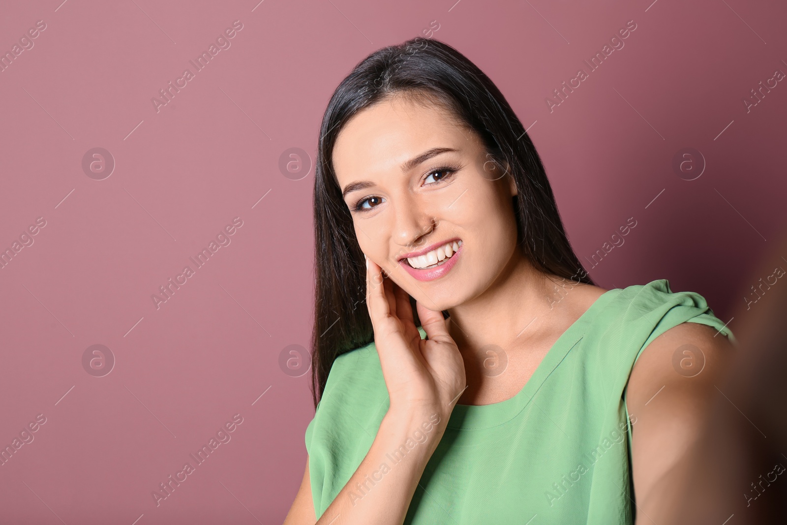 Photo of Young beautiful woman taking selfie against color background