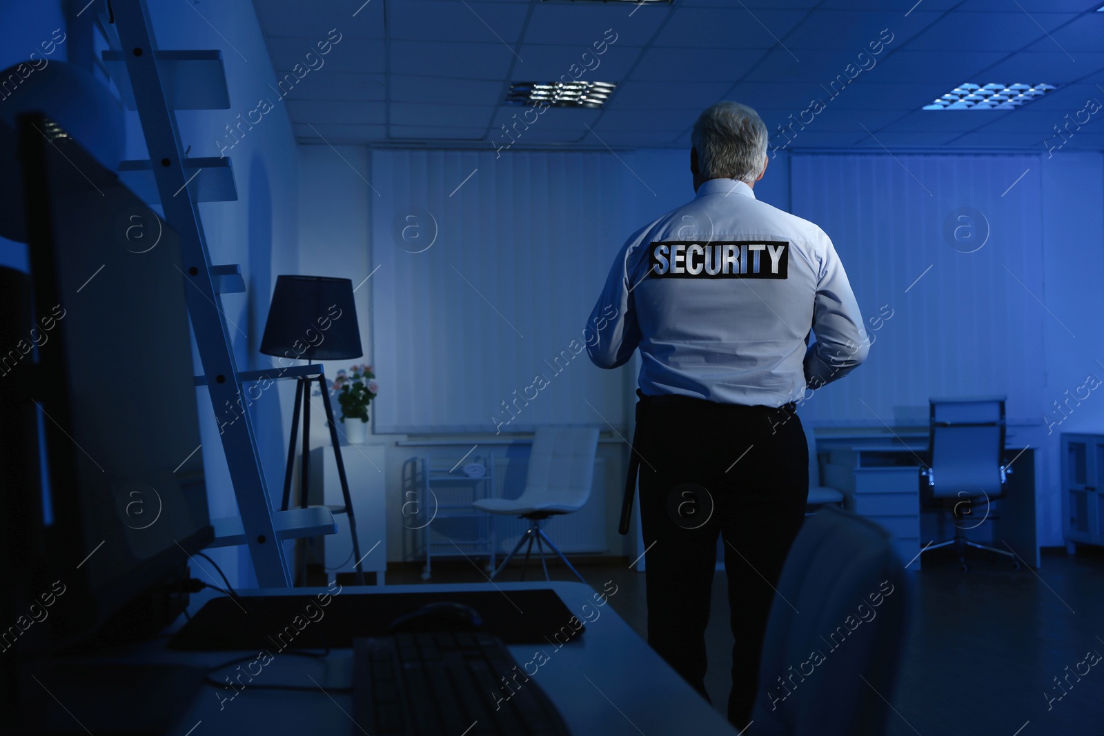 Photo of Professional security guard at work in dark office