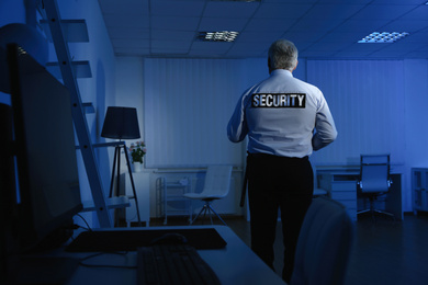 Professional security guard at work in dark office