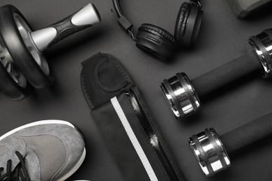 Photo of Sports equipment and headphones on black background, flat lay
