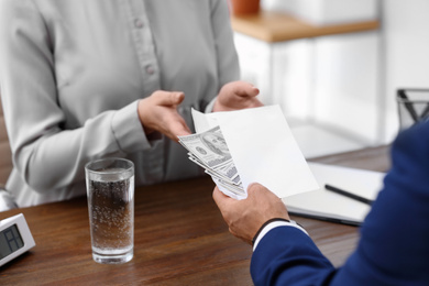 Man giving bribe money to woman at table, closeup