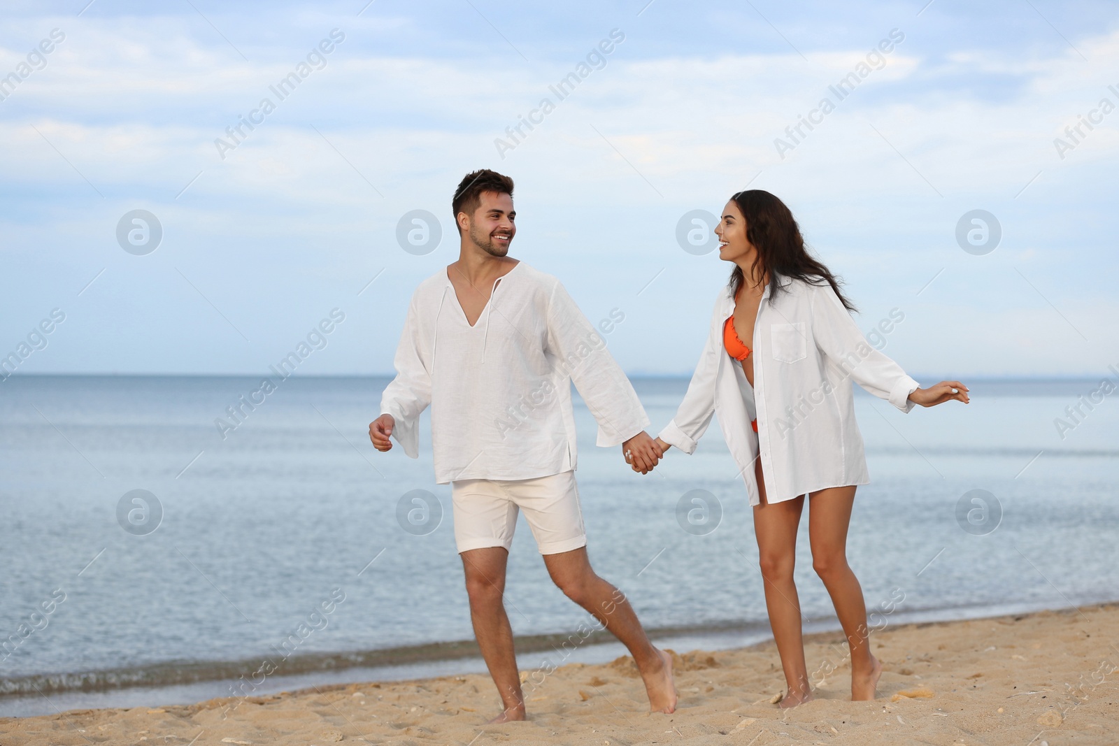 Photo of Happy young couple walking together on beach near sea