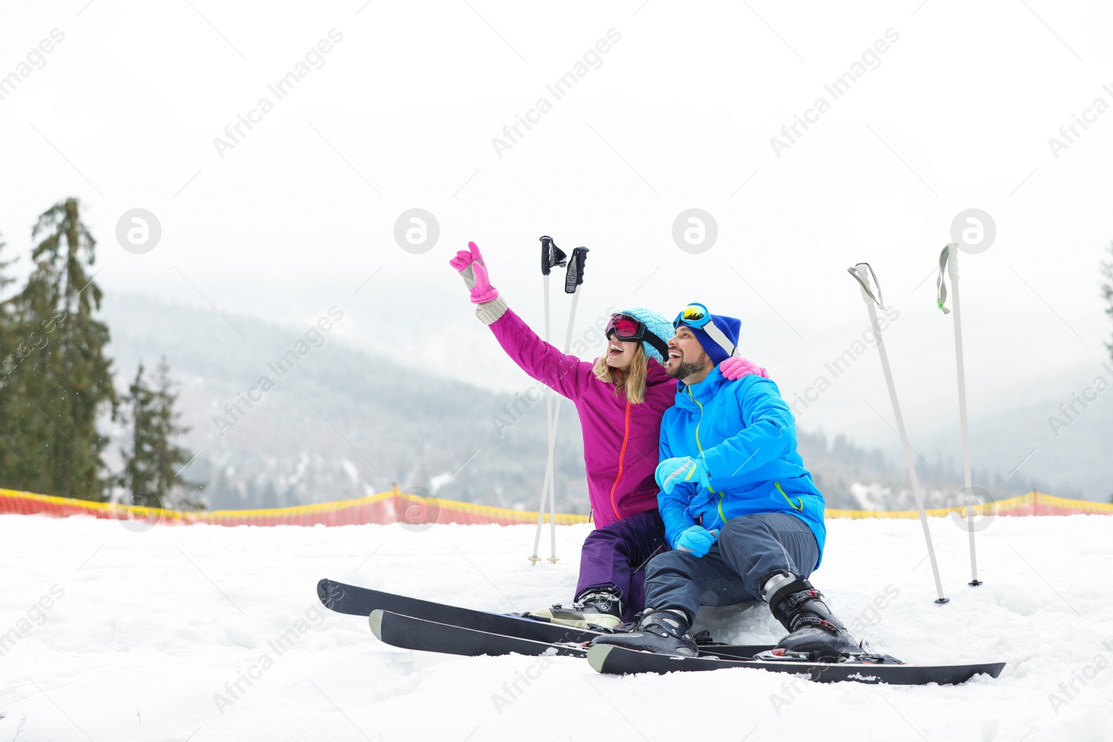 Photo of Couple of skiers on slope at resort. Winter vacation