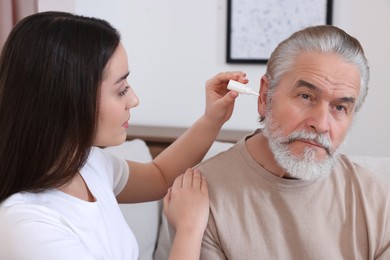 Young woman dripping medication into man's ear at home