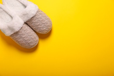 Photo of Pair of beautiful soft slippers on yellow background, top view. Space for text