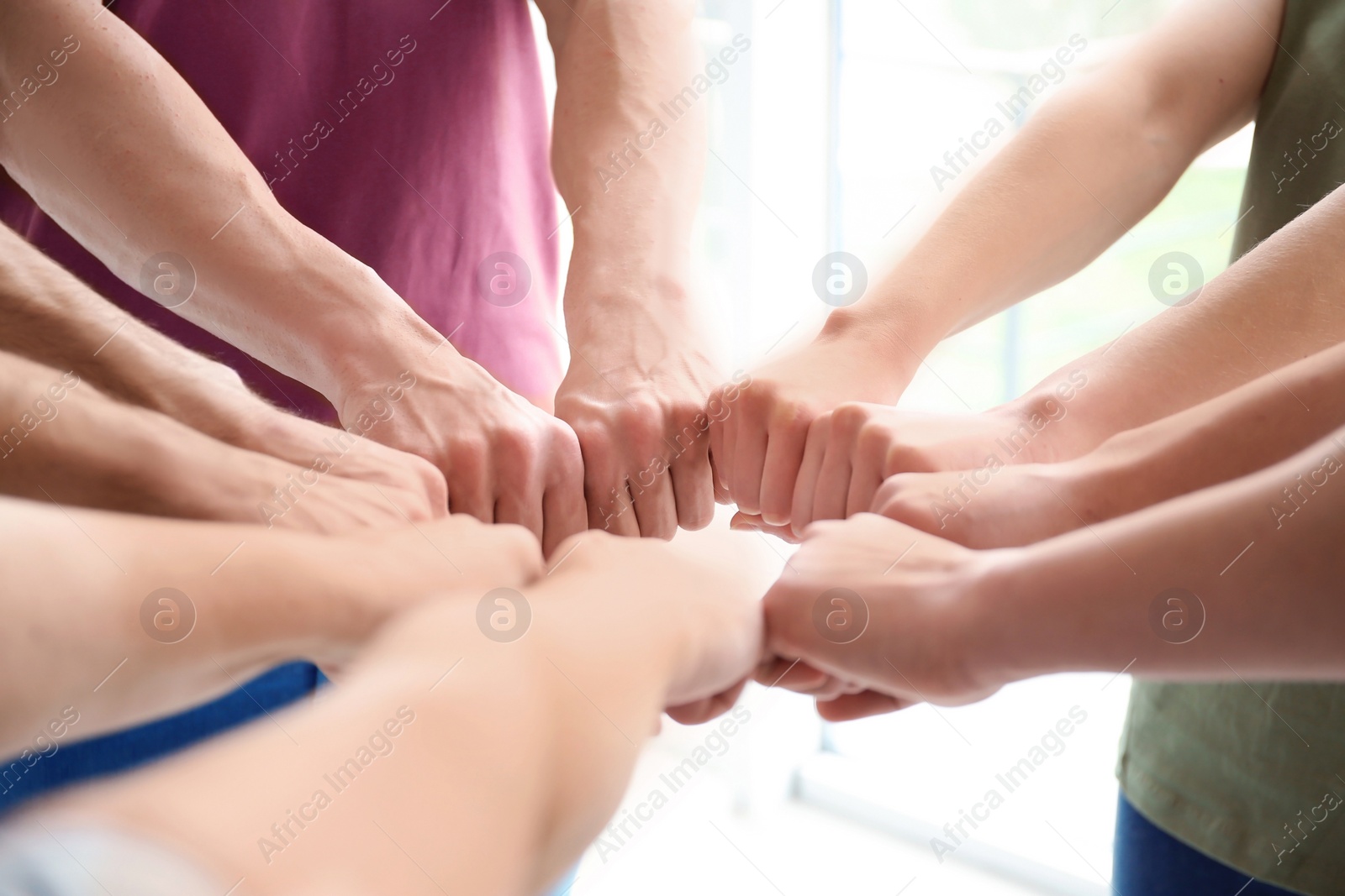 Photo of People putting fists together indoors. Unity concept