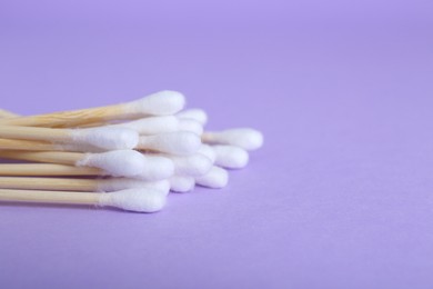 Photo of Wooden cotton buds on violet background. Space for text