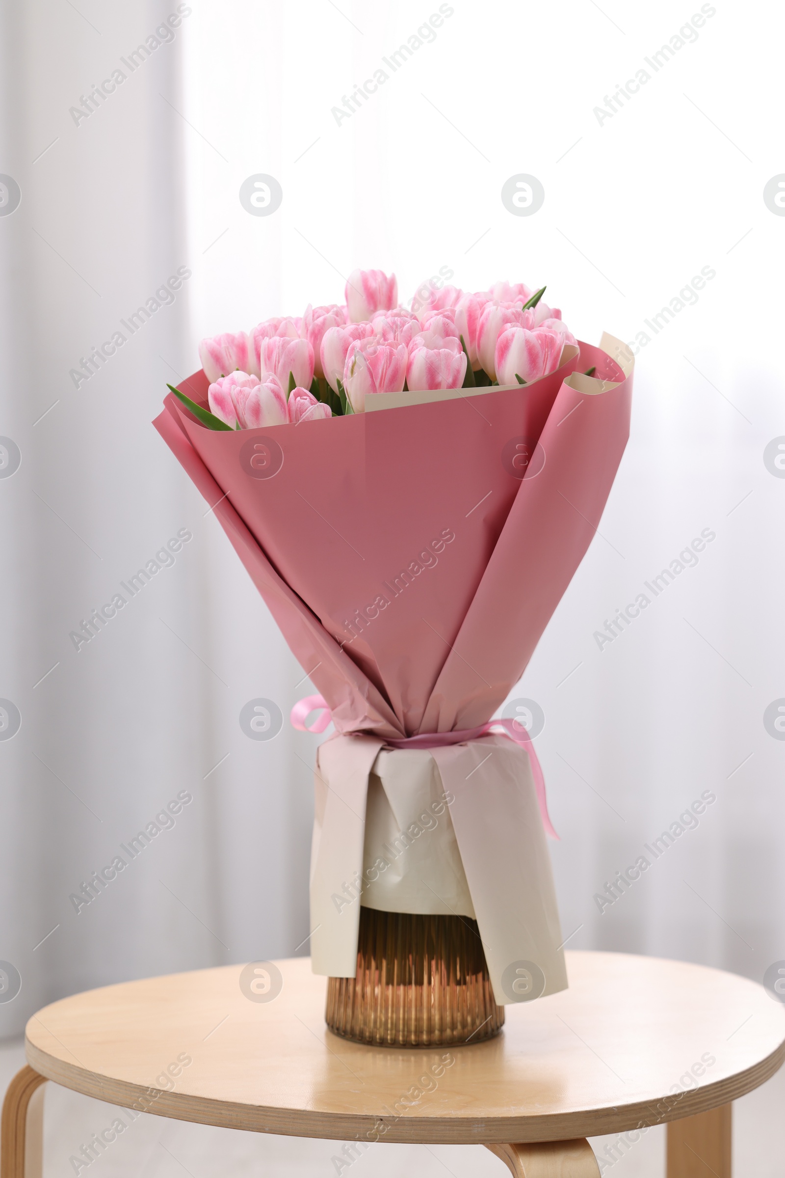 Photo of Beautiful bouquet of fresh pink tulips on table indoors