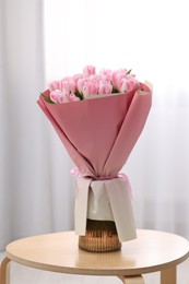 Beautiful bouquet of fresh pink tulips on table indoors