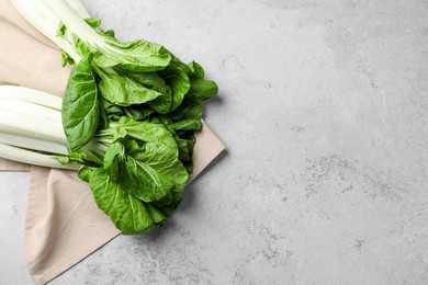 Photo of Fresh green pak choy cabbages with water drops on light grey table, flat lay. Space for text