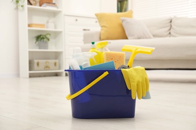 Photo of Different cleaning supplies in bucket on floor at home