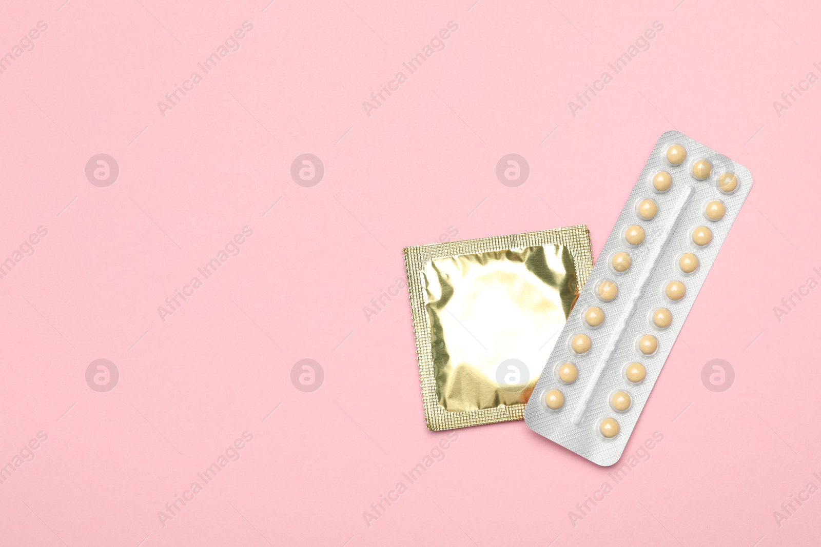 Photo of Condom and birth control pills on pink background, top view with space for text. Safe sex