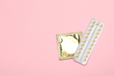 Photo of Condom and birth control pills on pink background, top view with space for text. Safe sex