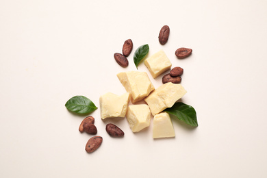Organic cocoa butter and beans on beige background, flat lay