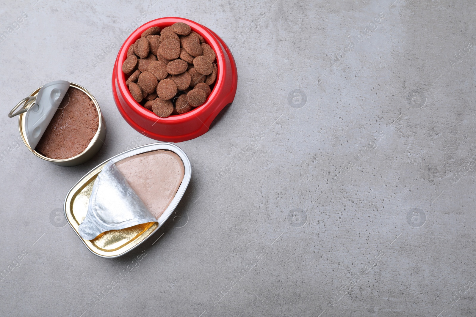 Photo of Wet and dry pet food on grey table, flat lay. Space for text