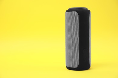 Photo of One portable bluetooth speaker on yellow background, space for text. Audio equipment