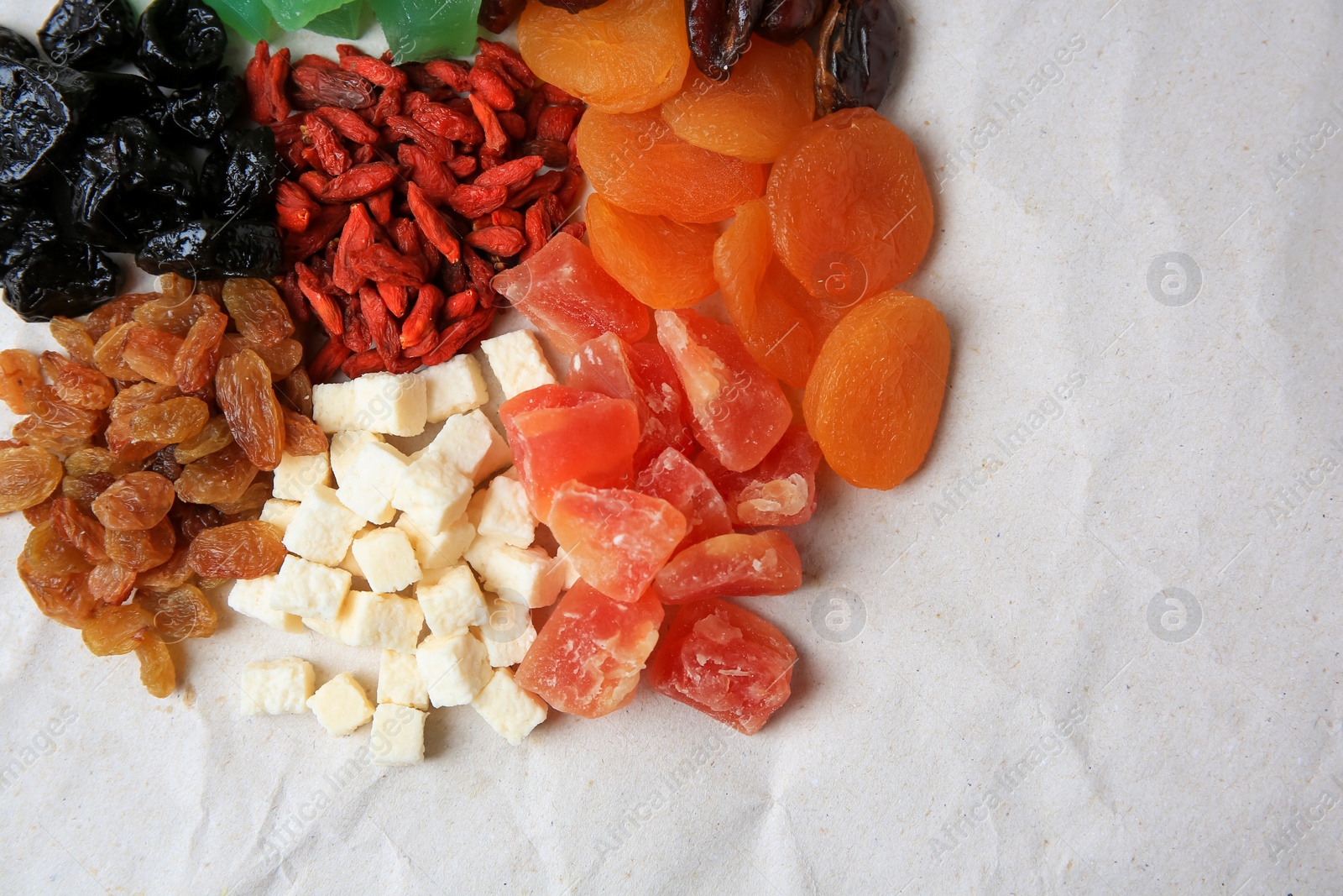 Photo of Pile of different dried fruits on white background, top view. Space for text